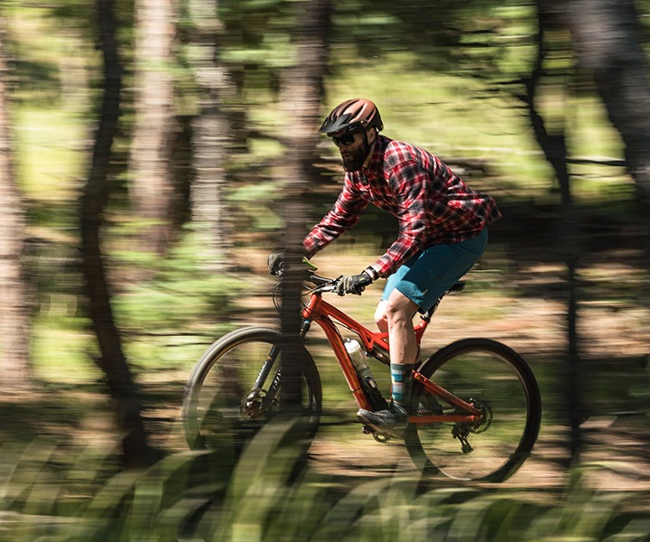 person riding a mountain bike on a trail in the woods