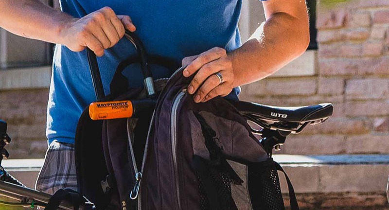 Cyclist putting u-lock in backpack