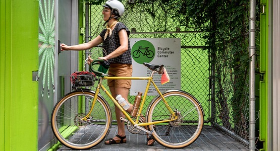 A woman taking a yellow bicycle into a parking facility