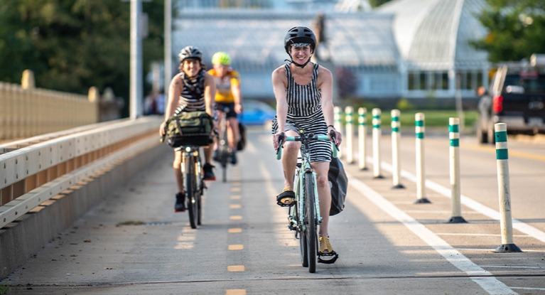 Three women smiling and riding in a bike lane.