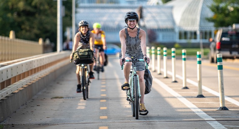 2 women riding touring bikes with pannier bags and handlebar bags in an urban setting.