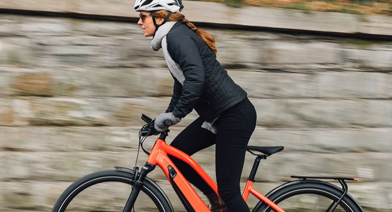 A person riding a Specialized Vado E-bike along a stone wall