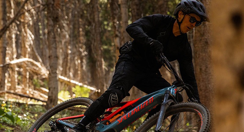 A person riding a Specialized Levo SL through the woods.