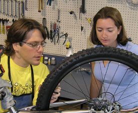 Our trained mechanic showing a woman the wheel of a bike.