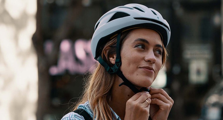 A woman putting on a bicycle helmet