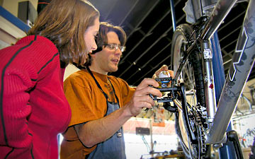 A mechanic showing a woman the pedals on a bike.