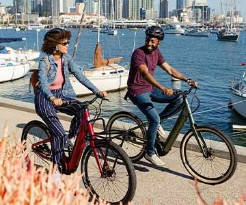 Two people riding bikes along a pier