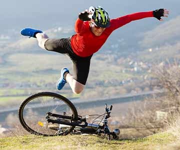 A man leaping from his bike onto a grassy hill