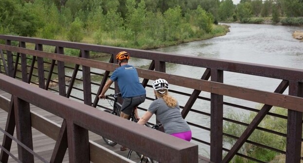 People biking on a bridge over a river