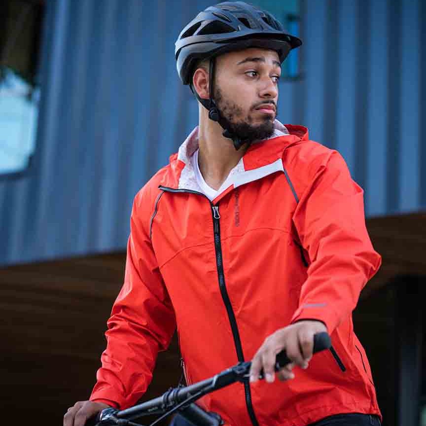 A man on a bike wearing a Showers Pass red bicycle jacket