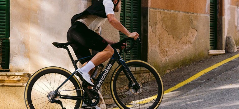 A bike rider resting on a Cannondale Synapse Carbon bike on the road