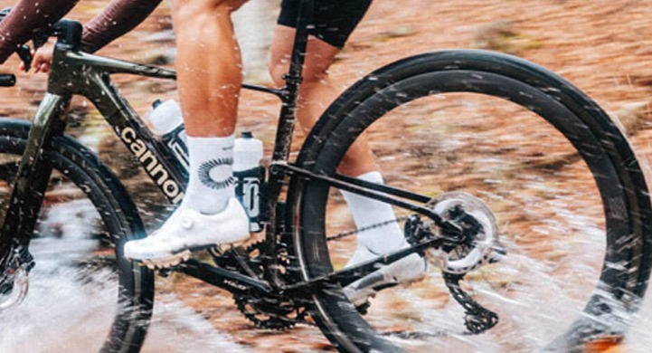 A bike rider riding a Cannondale Topstone bike through puddles