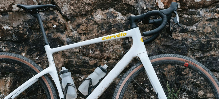 A Cervelo Aspero white gravel bike leaning against a stone wall
