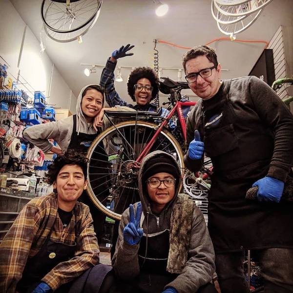 “Five members of the Bicycle Habitat staff standing around a bike.