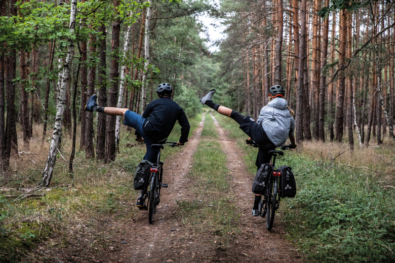 Two mountain bikers riding with left legs in the air