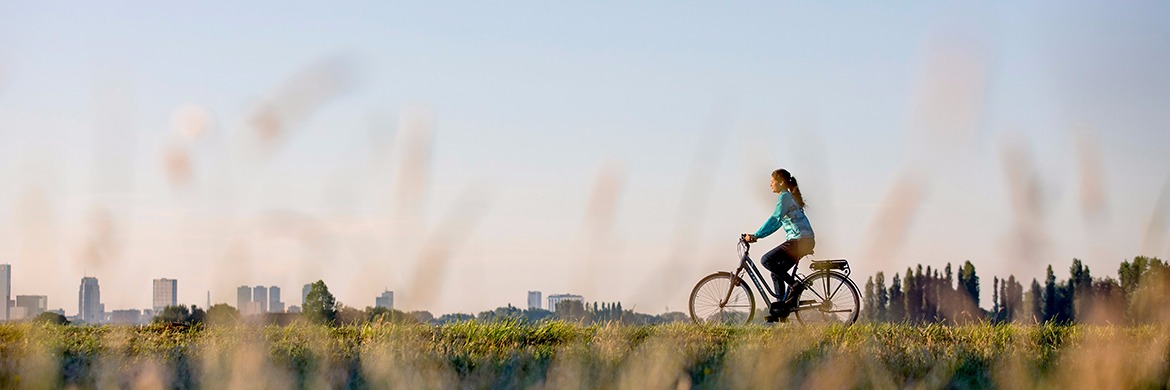 woman riding a bike with a city skyline in the distance