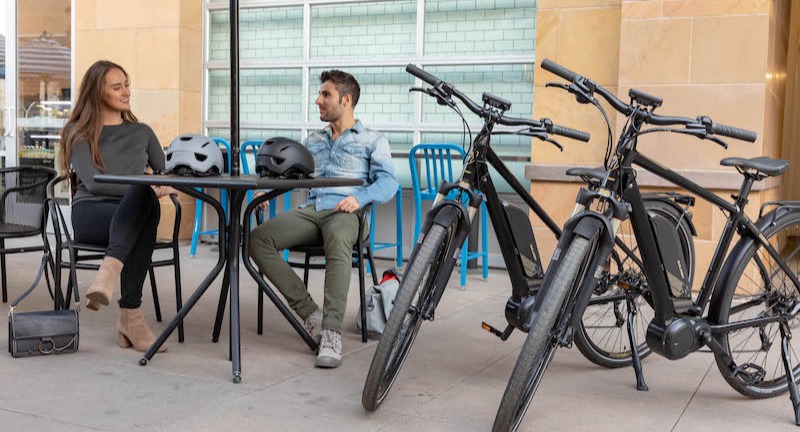 a couple relaxing at a table next to their electric bikes