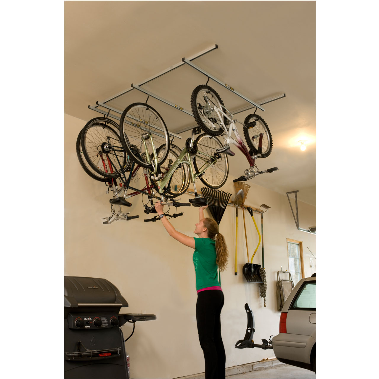 "woman hanging bike on overhead garage rack"