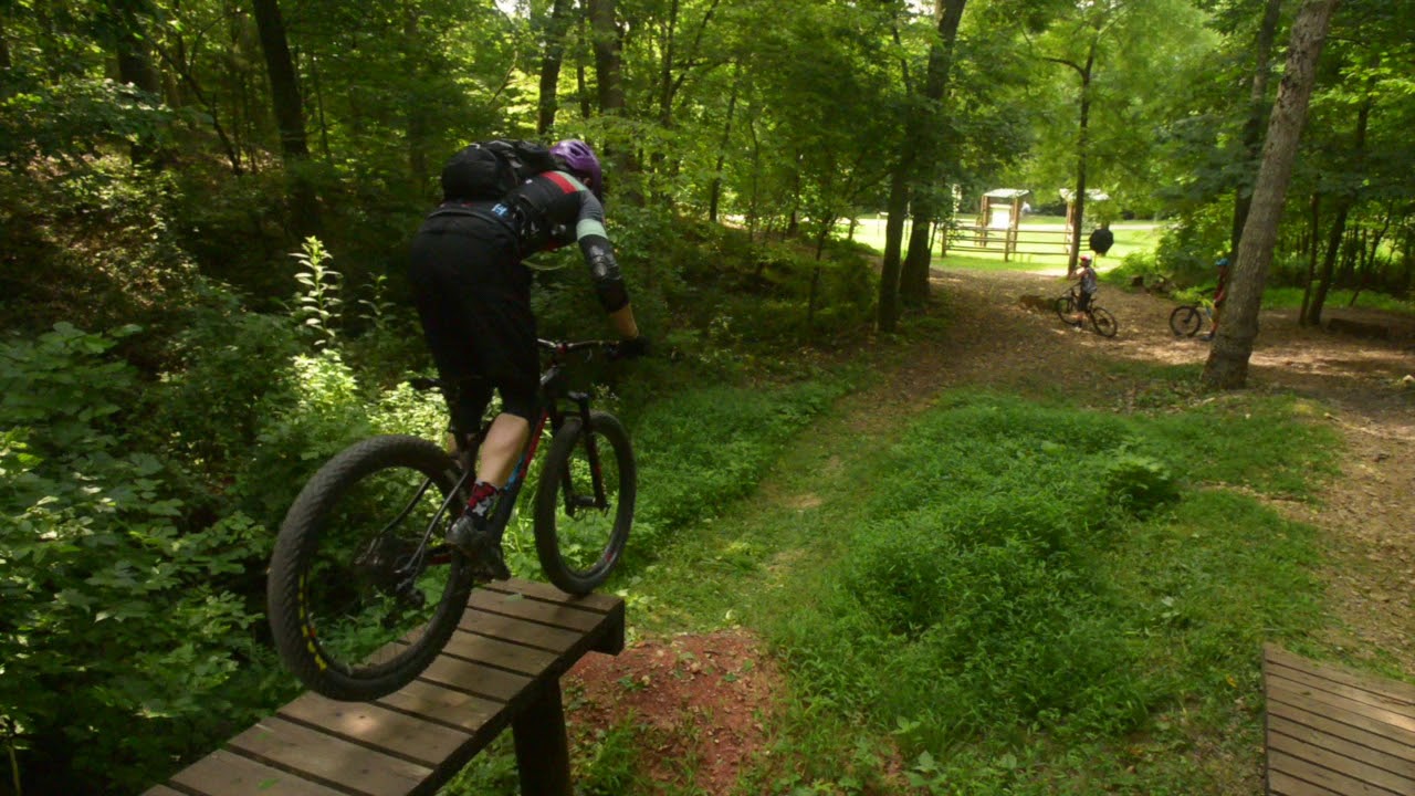 mountain biker riding off a wooden obstacle