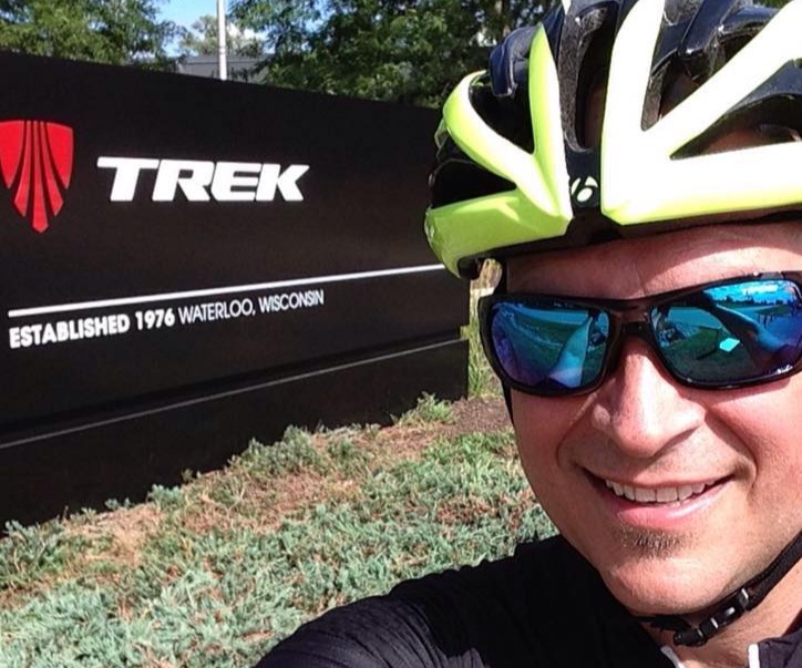 Steve in cycling gear by the Trek sign in Waterloo WI