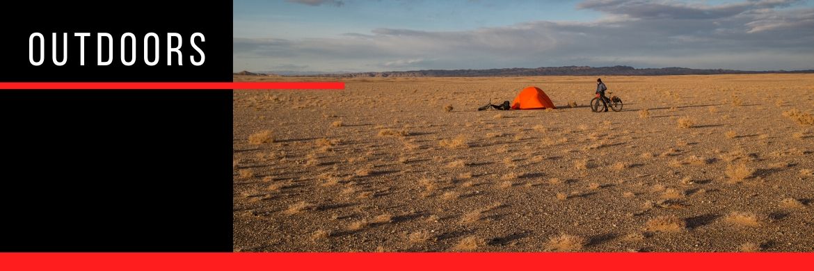 Image of a person in a bike next to a tent in the desert