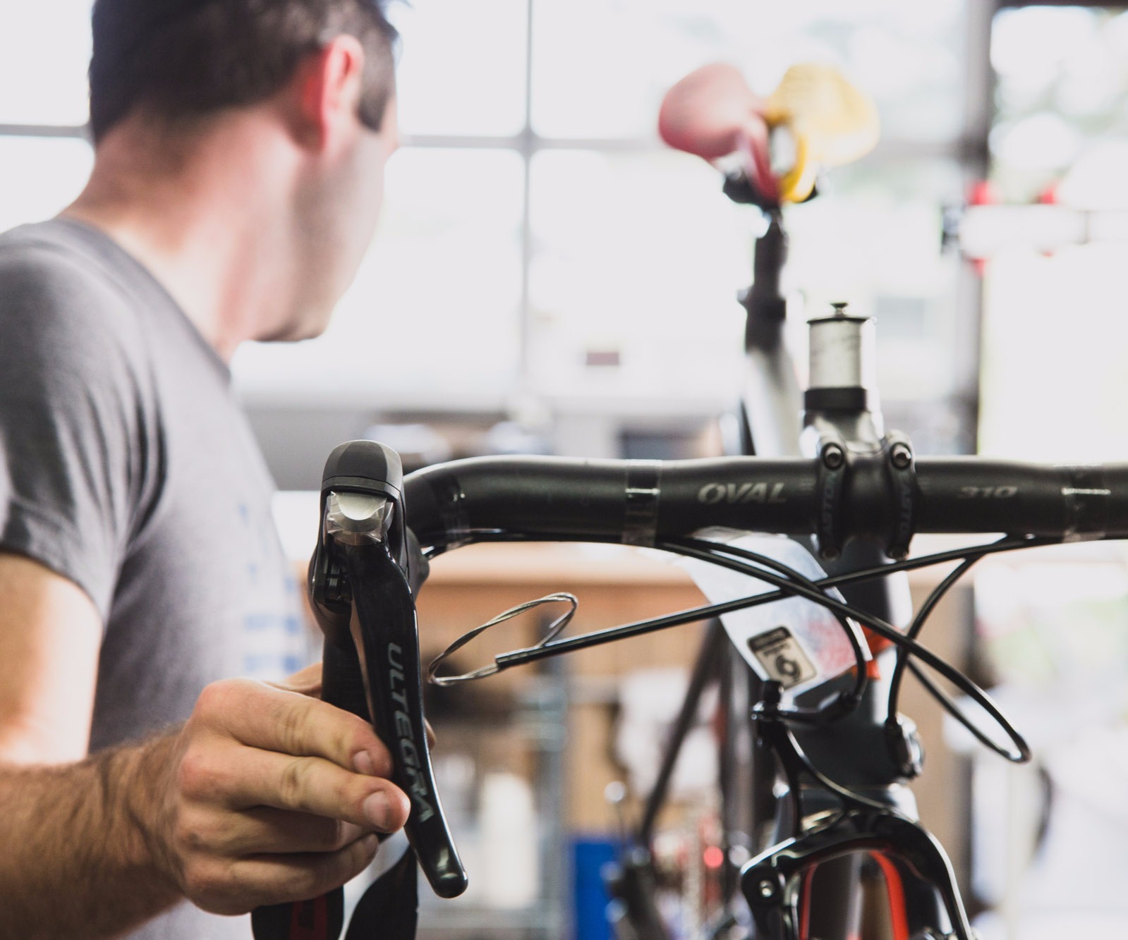 A bicycle mechanic adjusting a shifter in a repair shop.