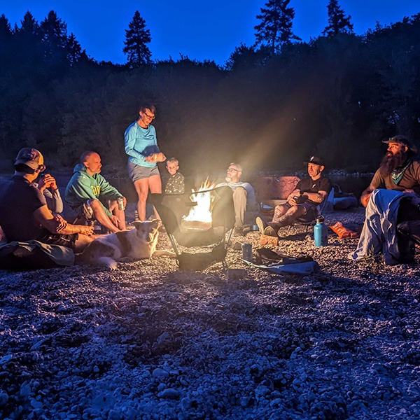Several people sitting around a campfire