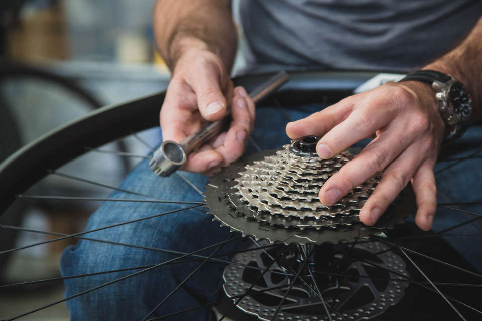 Image of a mechanic working on a bike's drive train