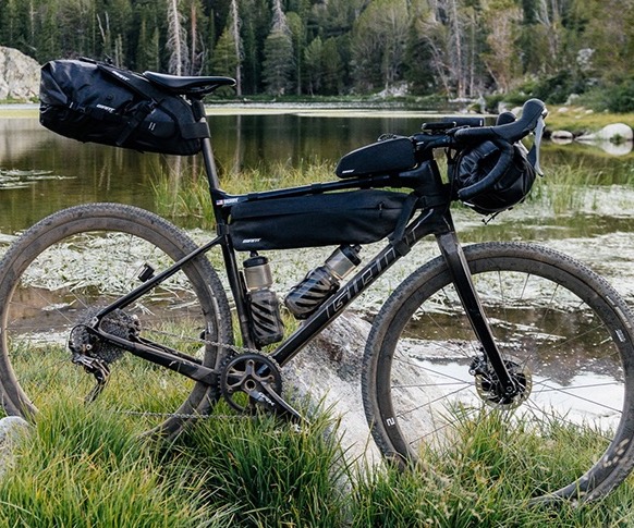 Bike by a river with packs filled with camping gear.