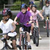 5 children riding bikes and smiling.