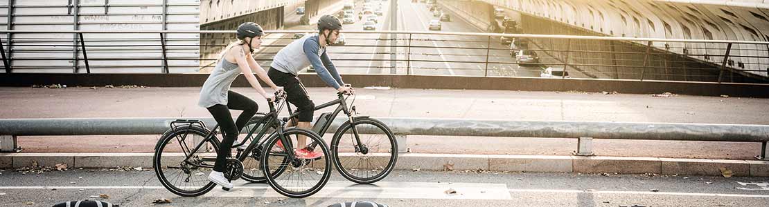 two cyclists riding city/hybrid bikes across city bridge