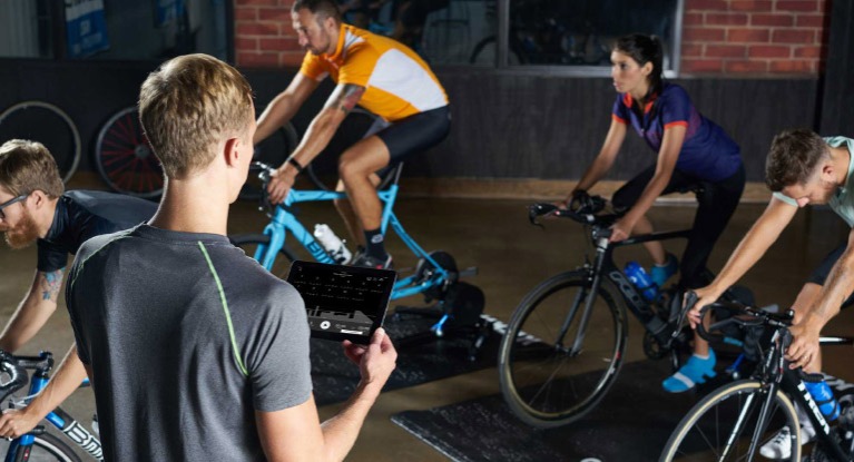 People working out on bikes with trainers and instructor