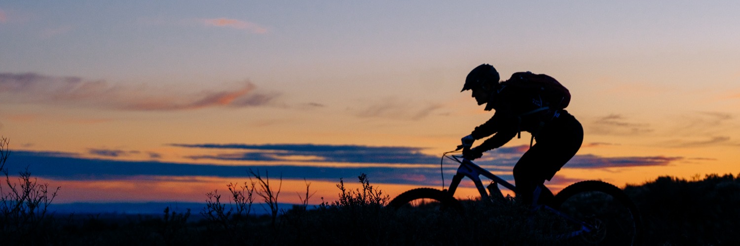 Image of a person riding their mountain bike while the sun is setting