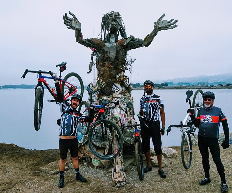 Group of cyclists in front of a sculpture