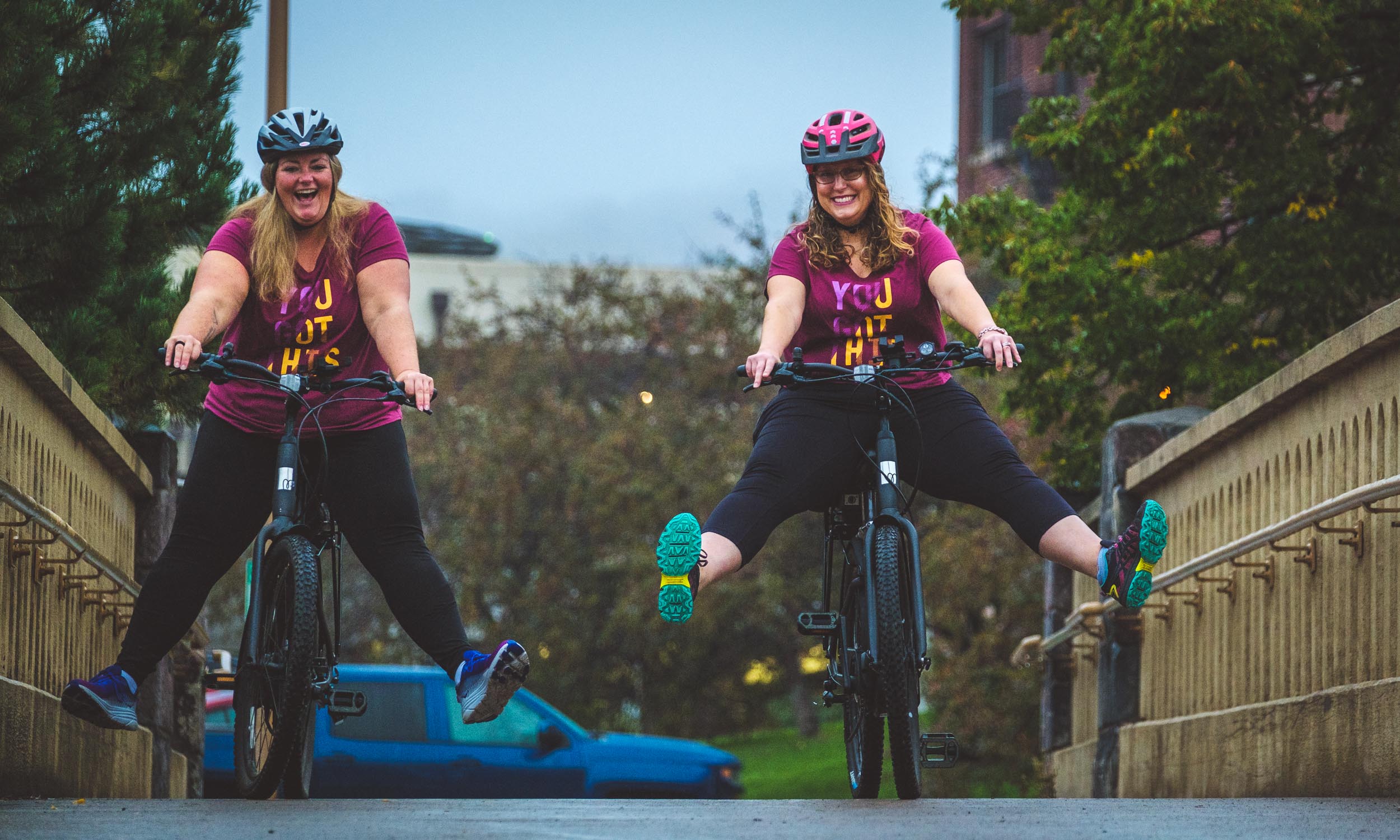 Two women smile wide riding their Momentum Lafree e-bikes on the Lakewalk in Duluth, MN bikes