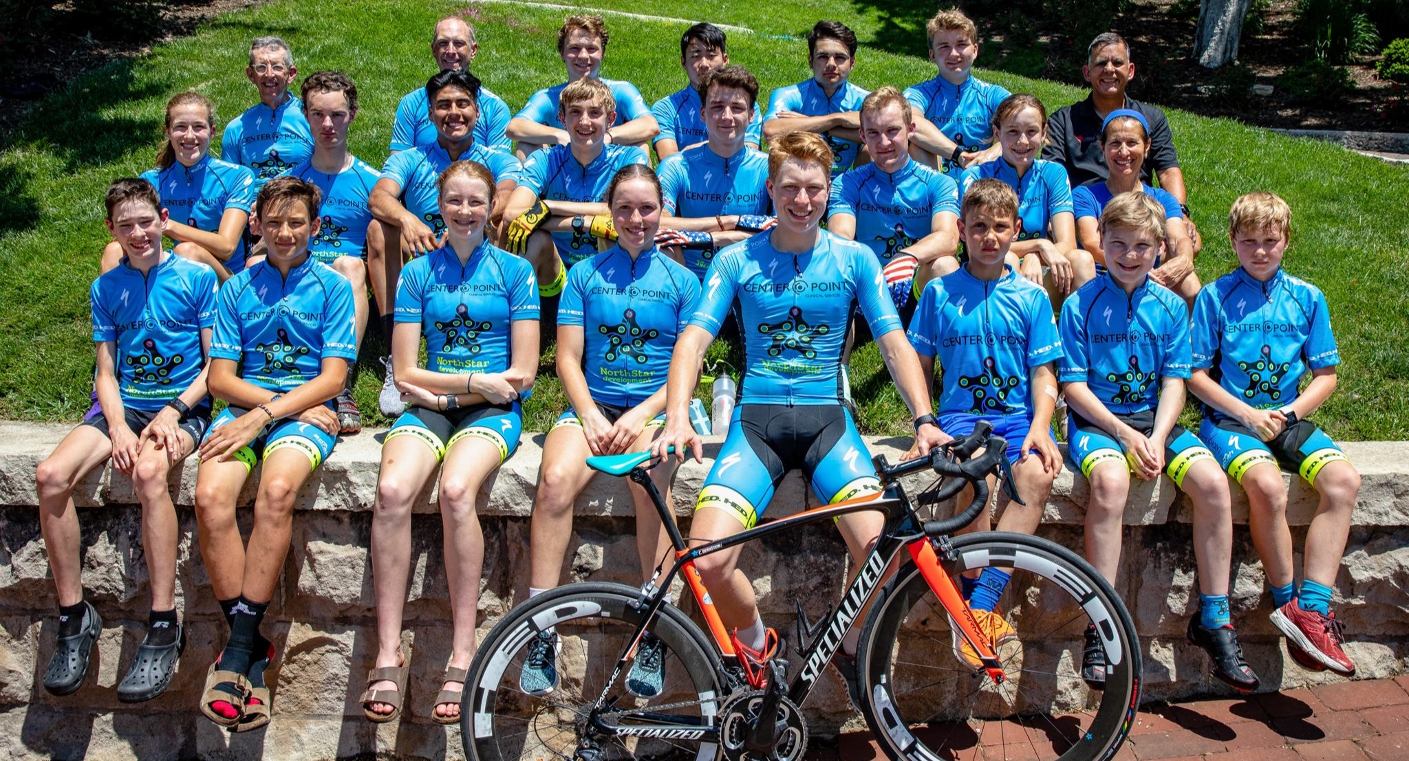 A NorthStar Development Cycling team photo on a racecourse behind a Specialized Tarmac team bike.