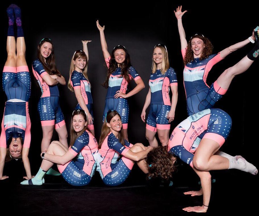 The Orion Women's Cycling Team Posing in front of a black background.
