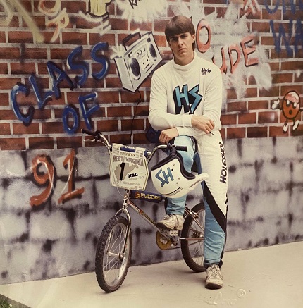 Man with his BMX bike posing in front of brick wall