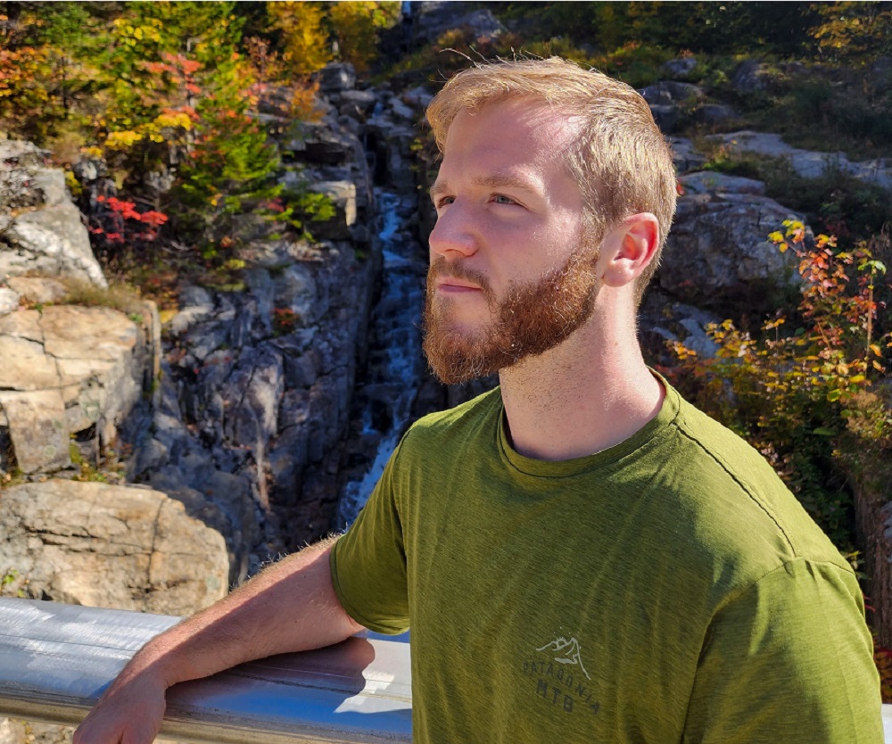 Man posing in front of a waterfall during the fall