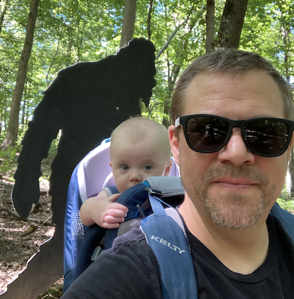 Man with child posing in front of sasquatch