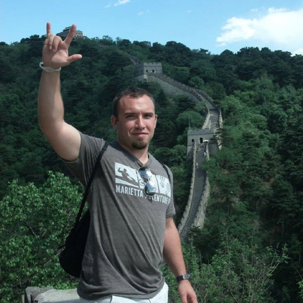 Man posing in front of Great Wall of China