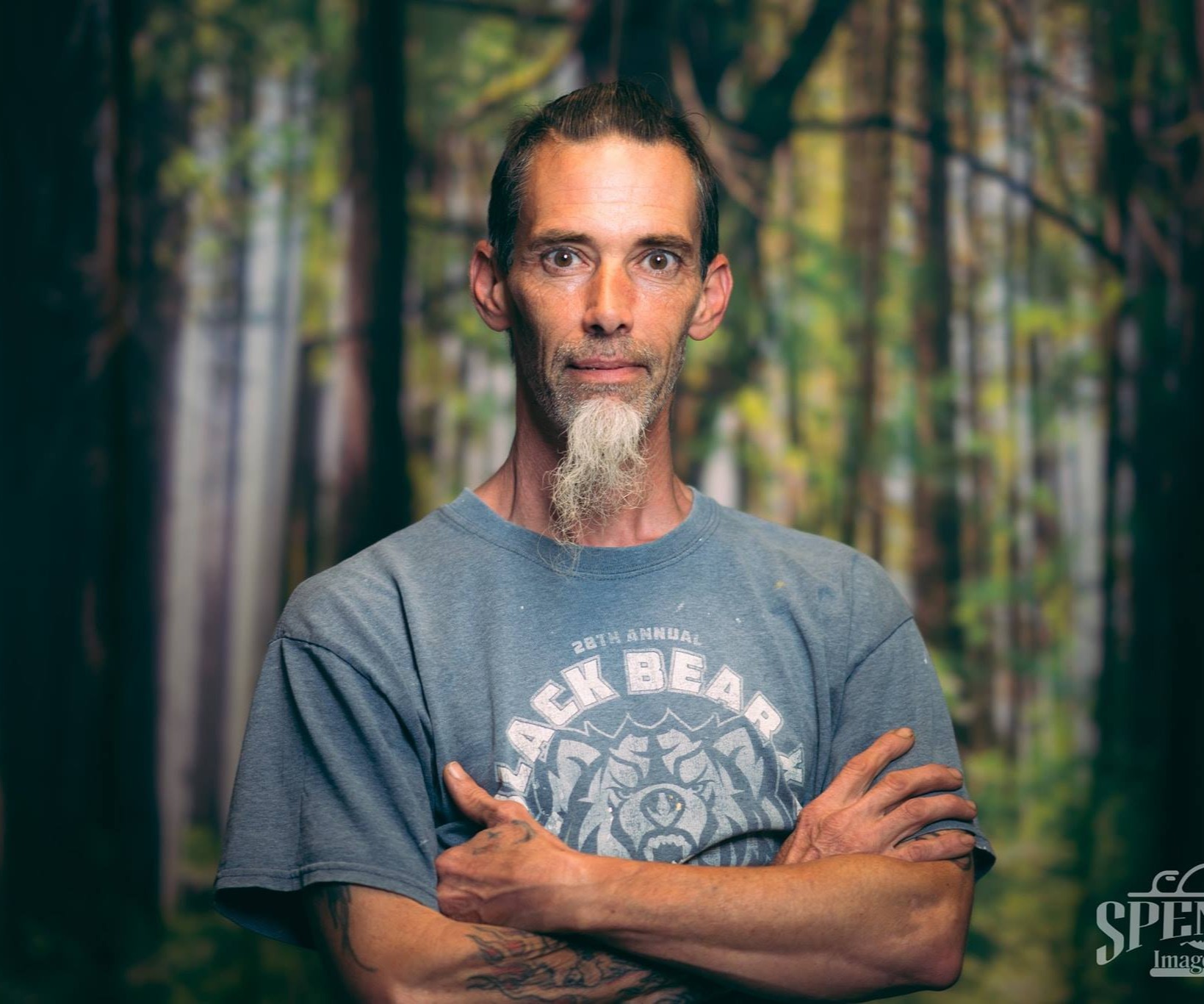 Man posing in front of a background depicting the woods