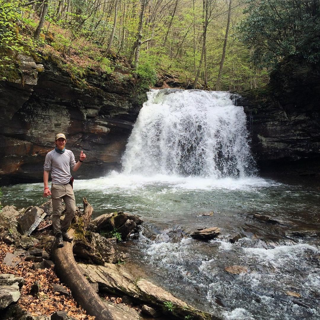 Man posing at base of a waterfall