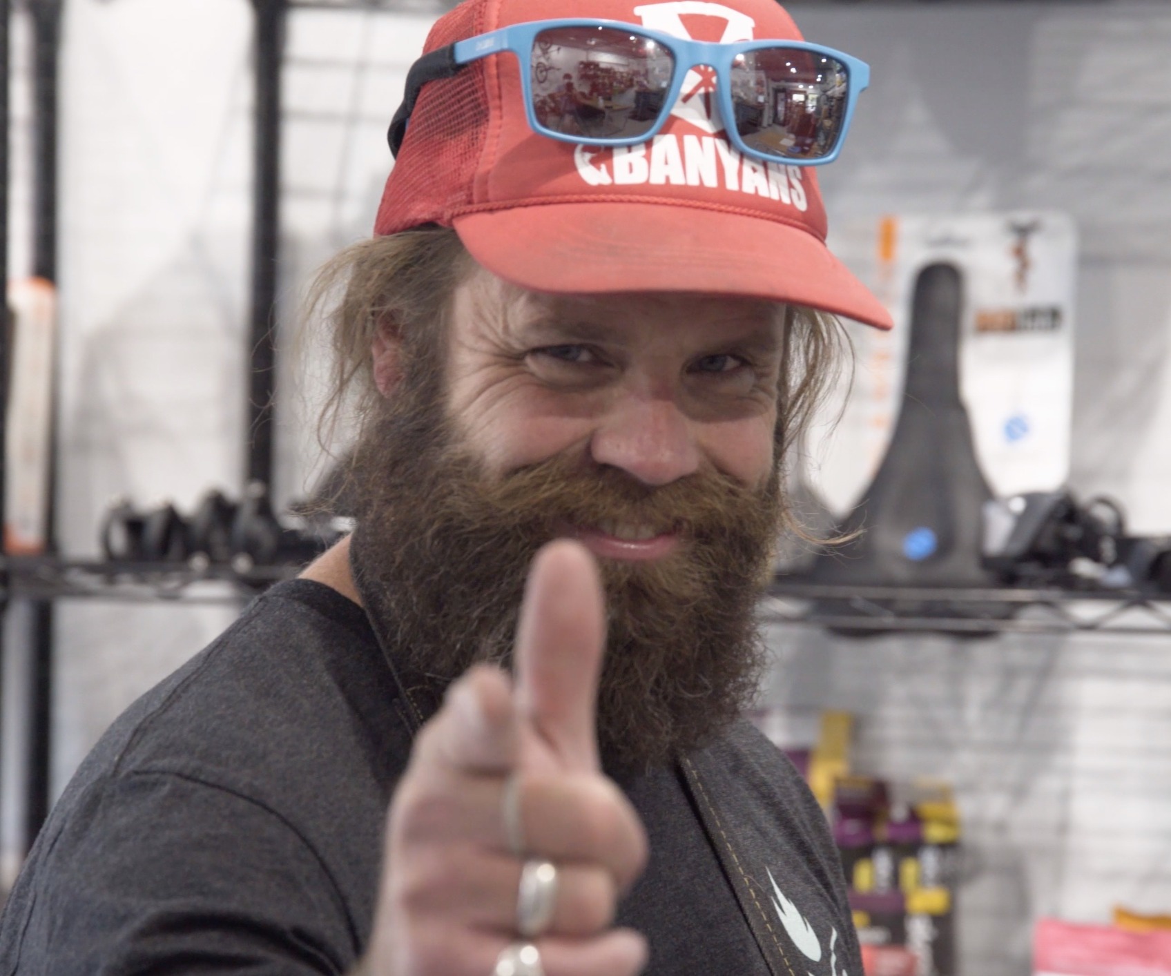 Smiling shop employee with a beard, hat and sunglasses. 