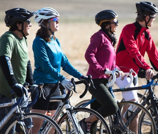 Four cyclists lined up and staring off into a cold, grassy field.