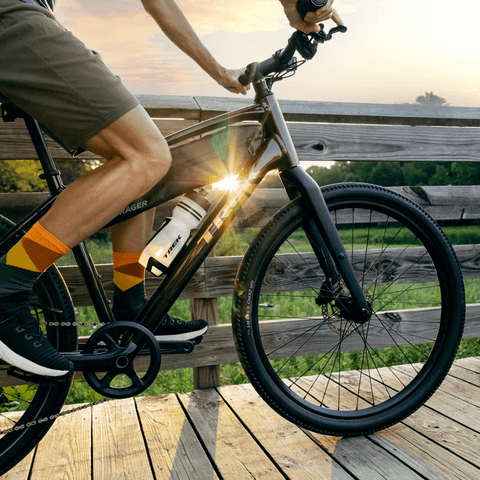 A man riding a Trek bike while the sunset shines behind him.