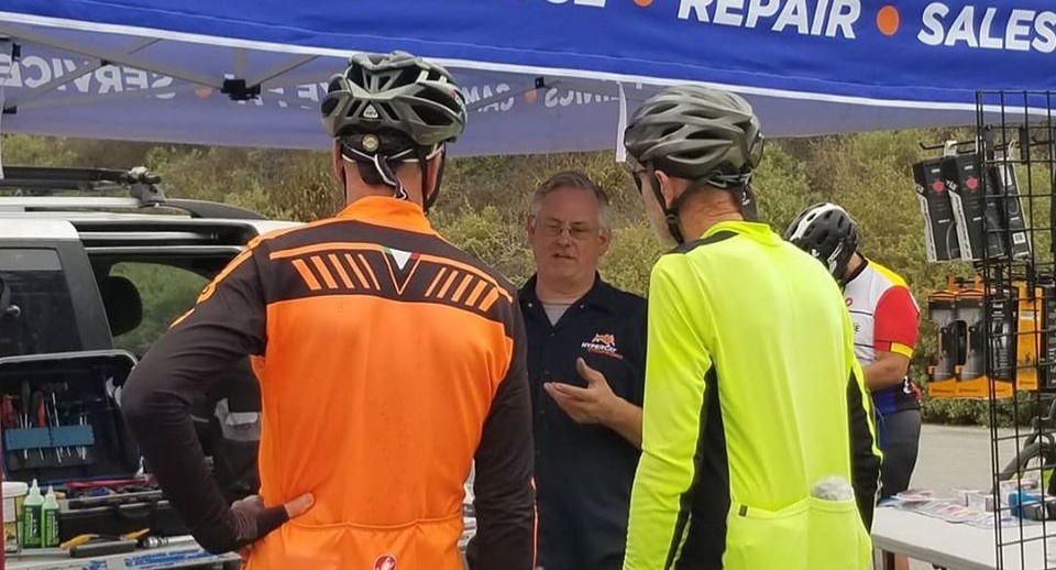 Philip Casanta helps two cyclists in the Hypercat tent at Cool Breeze Century sag stop.