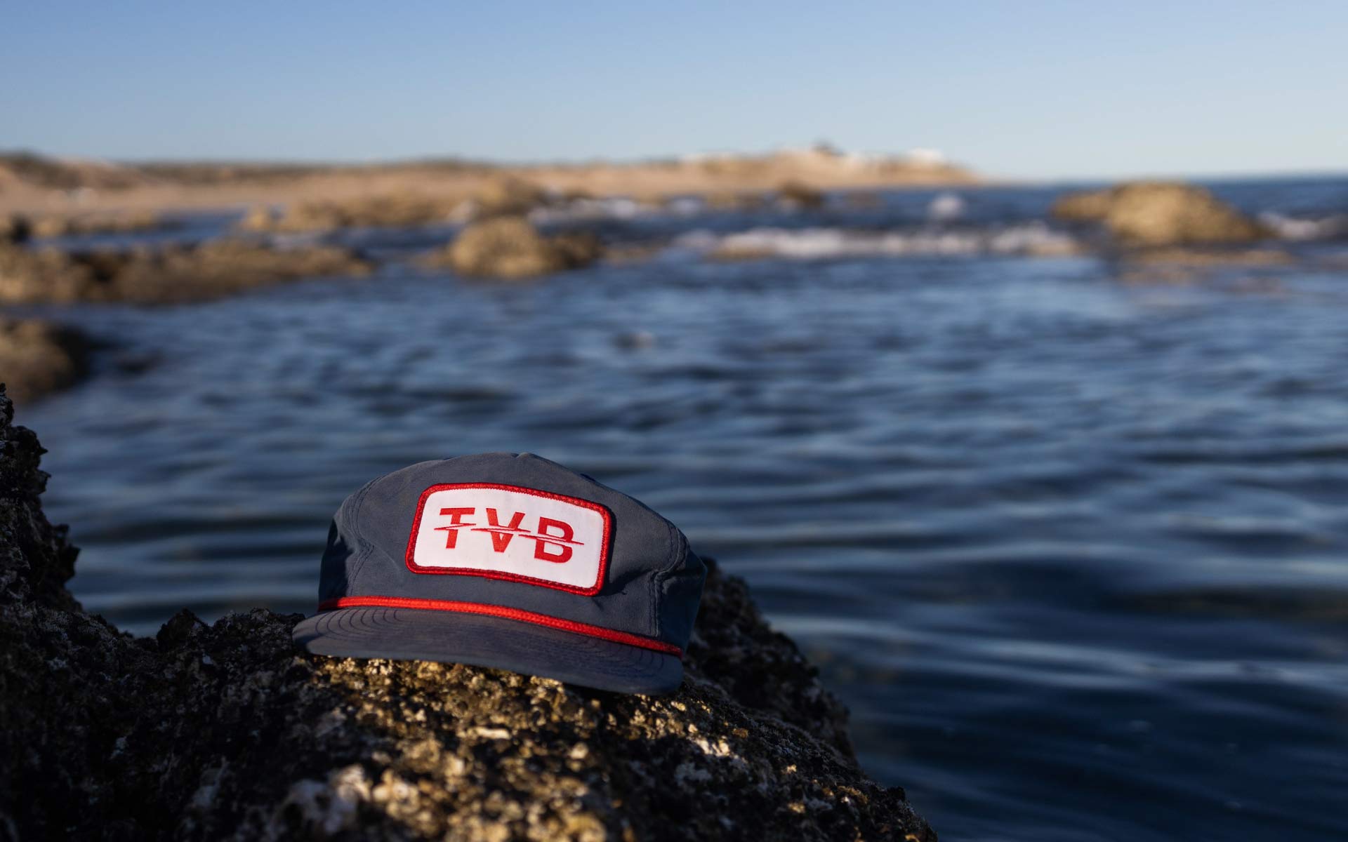 TVB hat on a rock by the ocean