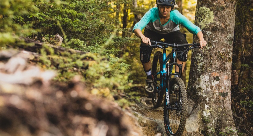 Woman cyclist riding a Kona mountain bike through the woods