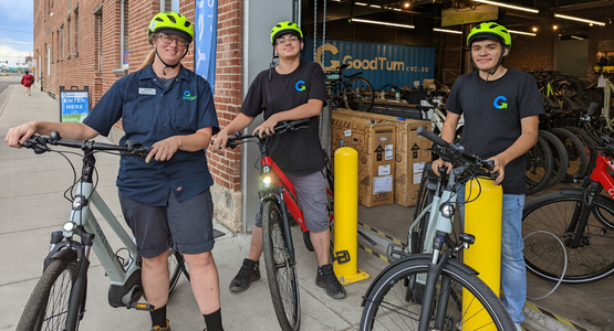 Three people standing next to eBikes with yellow helmets on
